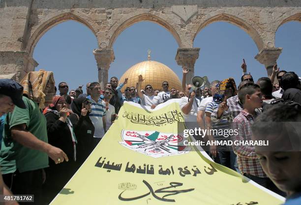 Palestinians hold a banner during a protest against balsphemy on July 24, 2015 following the Friday prayers at al-Aqsa Mosque compound in Jerusalem's...