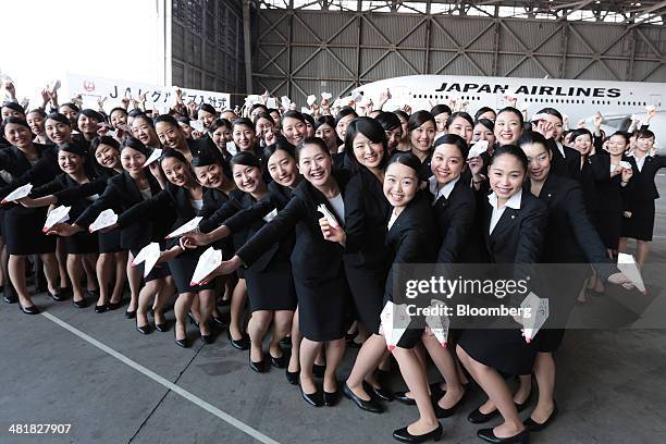 Japan Airlines Co. Group companies' new employees hold paper planes while posing for a photograph following a welcoming ceremony at the company's...