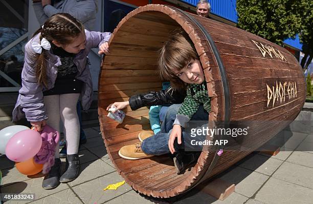 Children try to taste Diogenes' life in a barrel in the southern Russian city of Stavropol, on April 1, 2014. The sign on the barrel reads: Diogenes'...