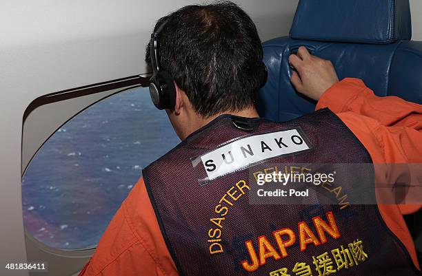 Masaki Sunako of the Japan Coast Guard looks out of a window on a Japan Coast Guard Gulfstream aircraft for wreckage and debris of missing Malaysia...