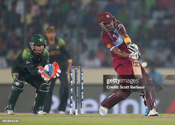 Dwayne Bravo of the West Indies hits a six as Kamran Akmal of Pakistan looks on during the ICC World Twenty20 Bangladesh 2014 match between West...