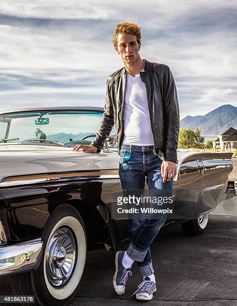 tall des années cinquante greaser gars avec une voiture classique convertible - classic leather photos et images de collection
