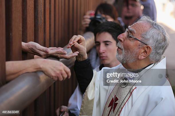 Bishop of Tucson Gerald Kicanas passes communion wafers through to the Mexican side of the U.S.-Mexico border fence during a special 'Mass on the...