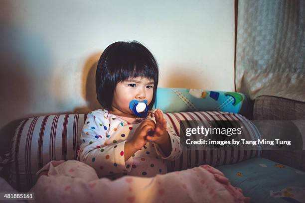 Baby girl sitting on the bed with quizzical face