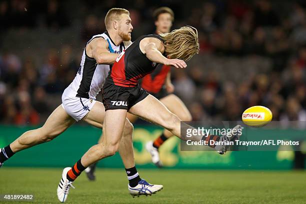 Dyson Heppell of the Bombers kicks the ball as Andrew Moore of the Power gives chase during the round 17 AFL match between the Essendon Bombers and...