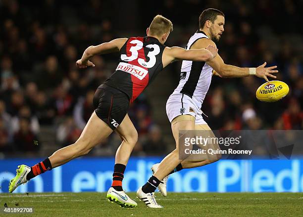 Travis Boak of the Power kicks whilst being tackled by Jayden Laverde of the Bombers during the round 17 AFL match between the Essendon Bombers and...