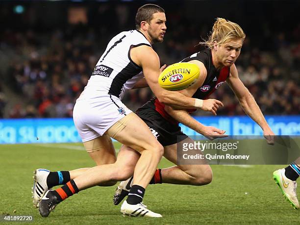 Ariel Steinberg of the Bombers handballs whilst being tackled by Travis Boak of the Power during the round 17 AFL match between the Essendon Bombers...