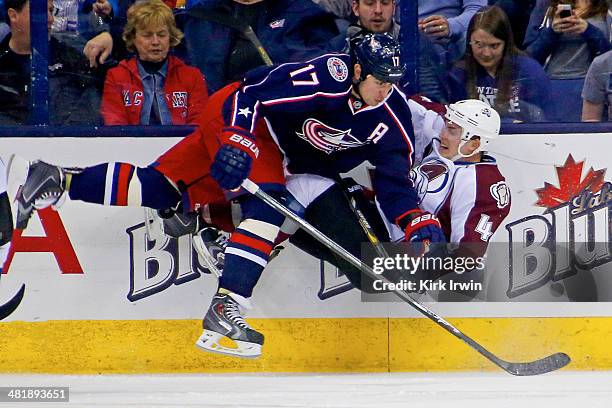 Brandon Dubinsky of the Columbus Blue Jackets checks Tyson Barrie of the Colorado Avalanche while chasing after the puck during the first period on...