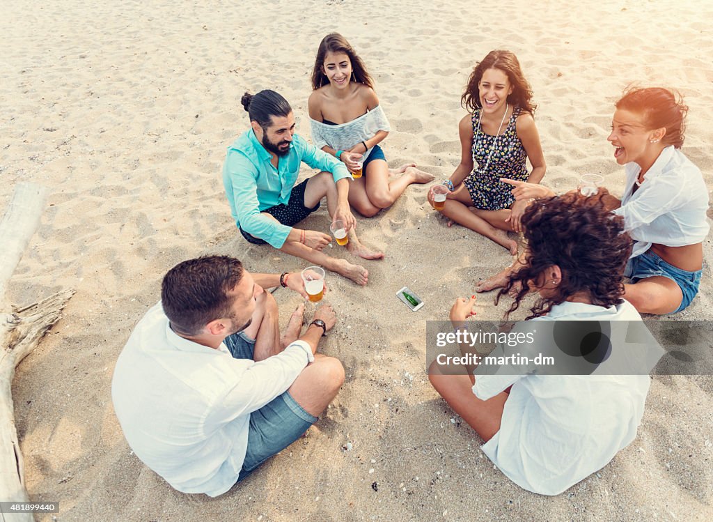 Young people playing spin the bottle at the beach