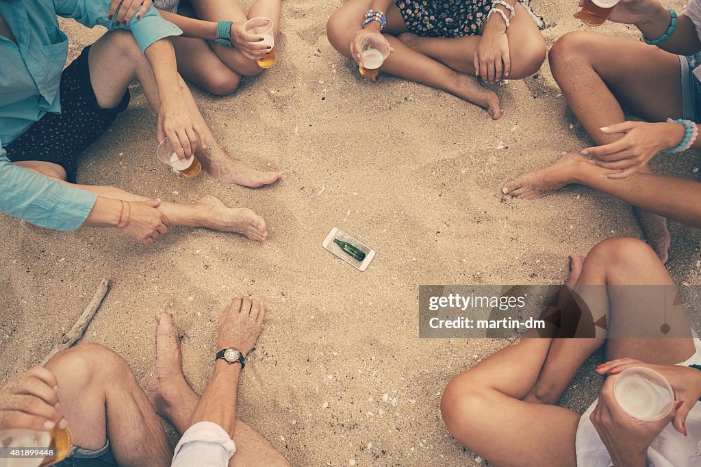 Junge Menschen spielen "spin the bottle" SPIEL am Strand