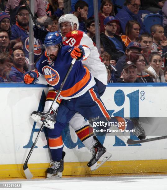 Scottie Upshall of the Florida Panthers is hit into the boards by Cal Clutterbuck of the New York Islanders during the third period at the Nassau...