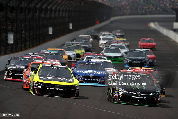 Kyle Busch, driver of the Monster Energy Toyota, and Paul Menard, driver of the Richmond/Menards Chevrolet, lead a pack of cars into turn one during...