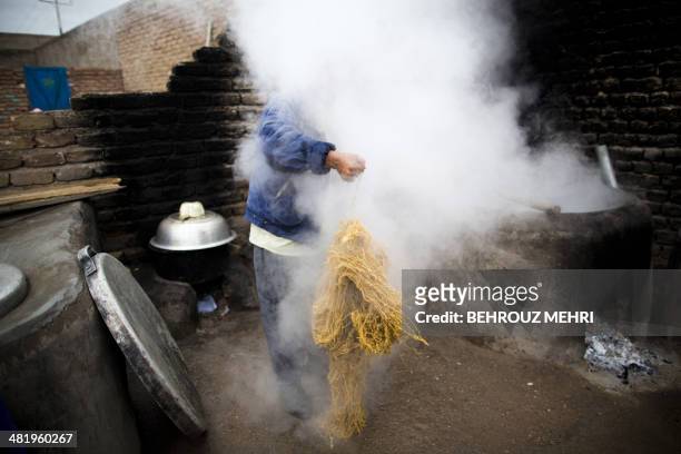 In this photograph taken on April 1 Afghan worker Mohammad Hossein takes threads out of boiling water after dyeing for carpets at a carpet...