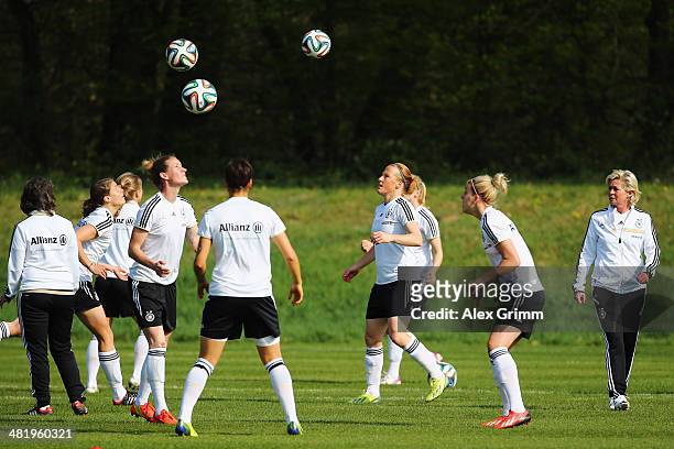 Head coach Silvia Neid of Germany walks past players exercising during a Germany Women's training session at the Commerzbank Arena training ground on...
