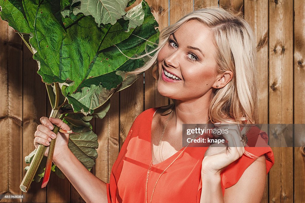Beautiful woman with rhubarb outdoors in summer