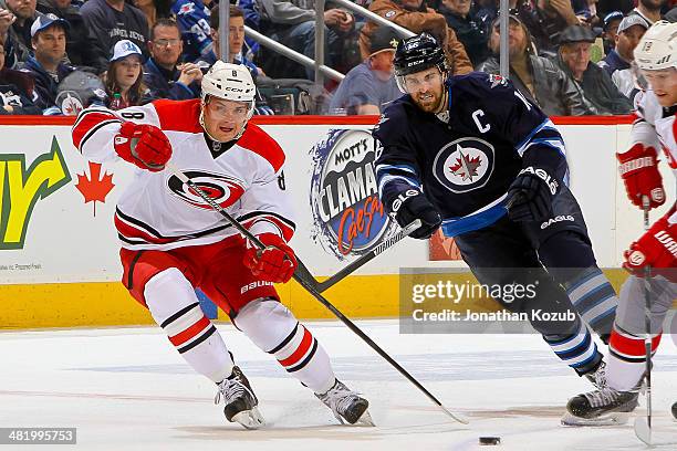 Andrei Loktionov of the Carolina Hurricanes plays the puck up the ice as Andrew Ladd of the Winnipeg Jets gives chase during first period action at...