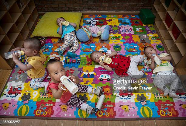 Young orphaned Chinese children drink milk from bottles at a foster care center on April 2, 2014 in Beijing, China. China's orphanages and foster...
