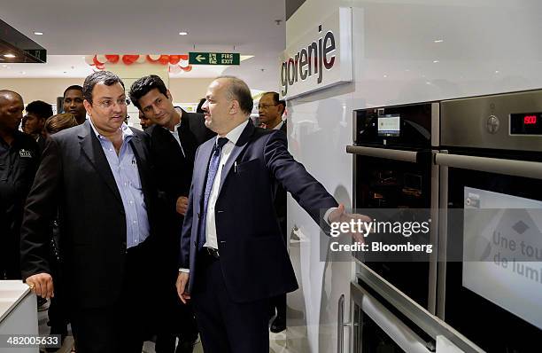 Cyrus Mistry, chairman of Tata Group, left, speak with Ajit Joshi, chief executive officer of Infiniti Retail Ltd., right, during a tour at the...