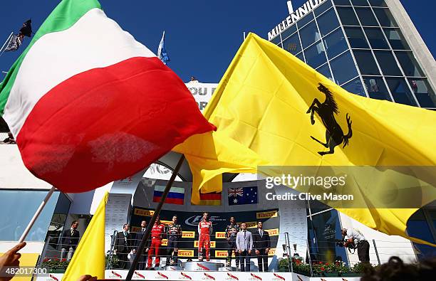 Sebastian Vettel of Germany and Ferrari celebrates on the podium next to Daniel Ricciardo of Australia and Infiniti Red Bull Racing, Daniil Kvyat of...