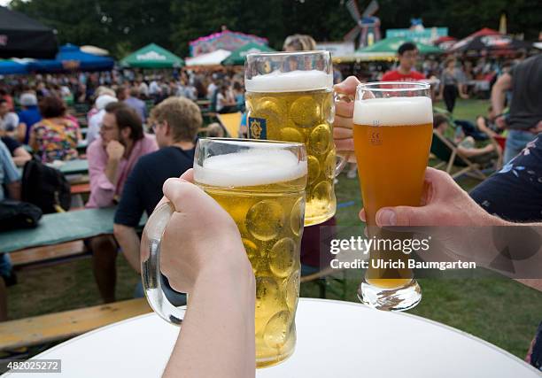 Beer festival in the Bonn Rheinaue leisure park. Toasting with filled beer glasses.