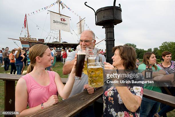 Beer festival in the Bonn Rheinaue leisure park. Toasting with filled beer glasses.