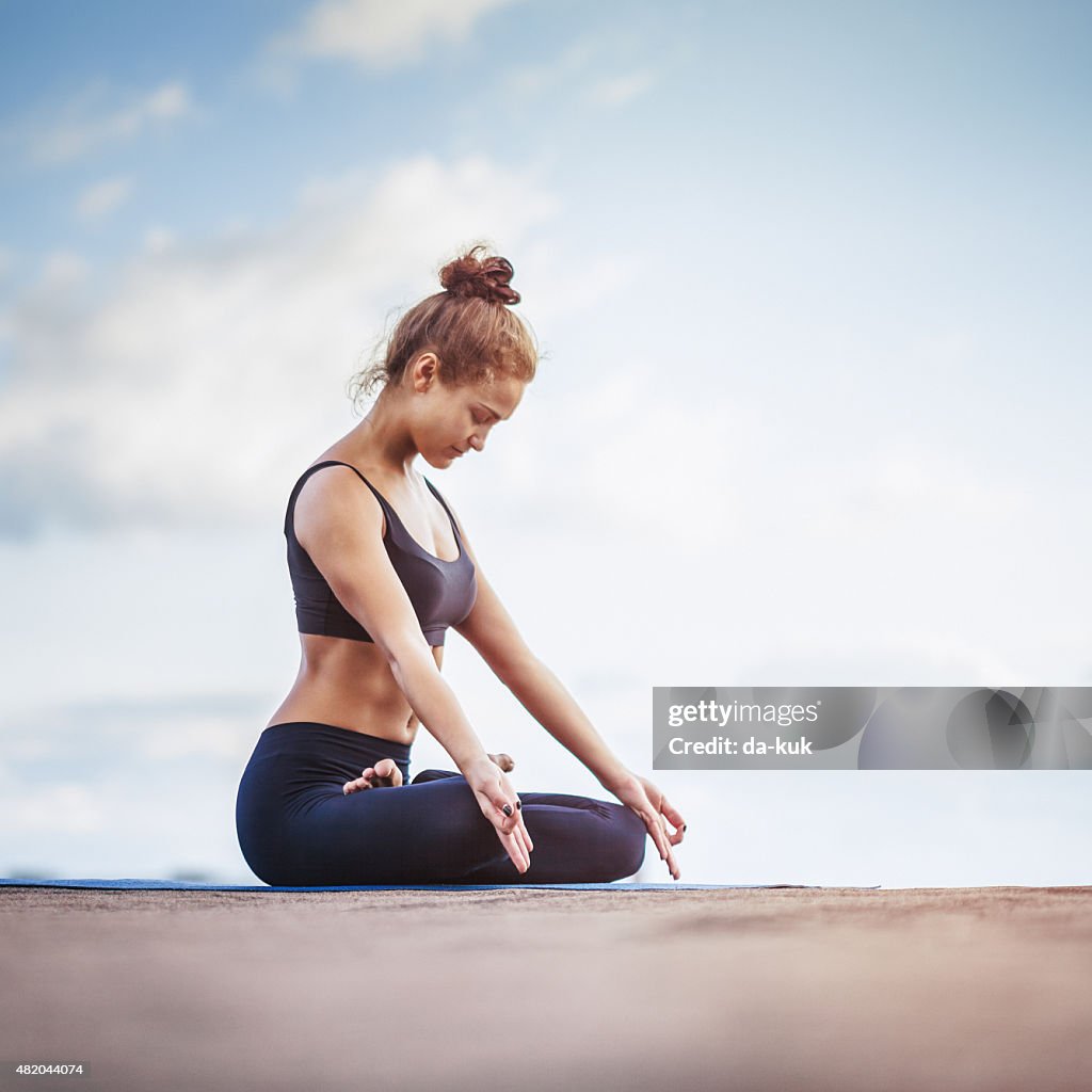 Mujer joven meditar al aire libre en una terraza