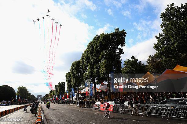 The Patrouille de France aerial display team flies overhead as the riders make their way down the Champs Elysees during the twenty first stage of the...