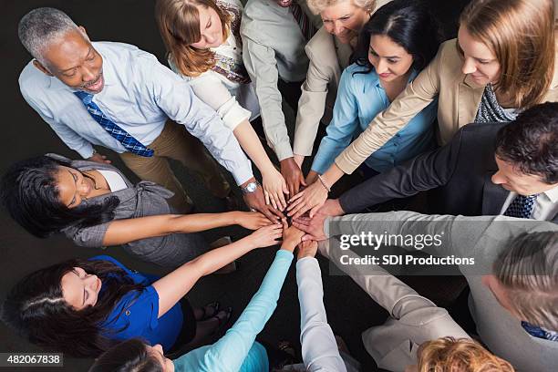 diverse business team with hands in huddle to celebrate success - team hands in huddle stock pictures, royalty-free photos & images