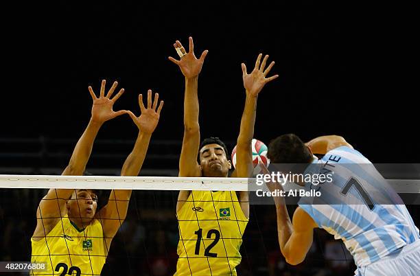 Facundo Conte spikes against Octavio Pinto, and Douglas Souza of Brazil during the Men's Volleyball finals at the Pan Am Games on July 26, 2015 in...