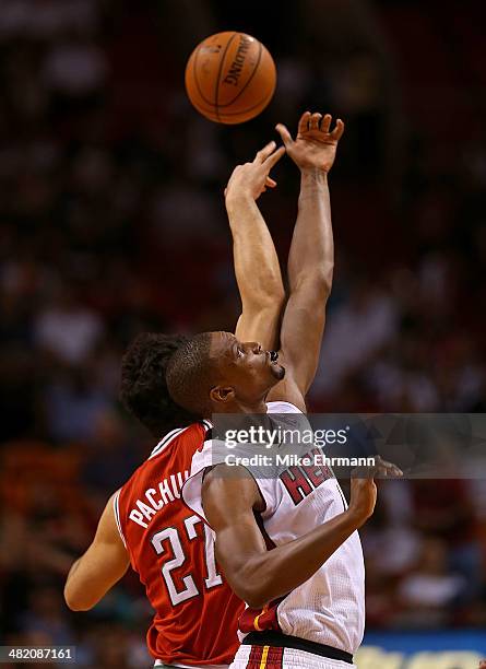 Chris Bosh of the Miami Heat and Zaza Pachulia of the Milwaukee Bucks go up for a jump ball during a game at American Airlines Arena on April 2, 2014...