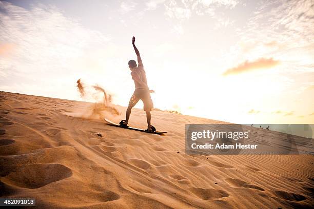 a young man riding on the genipabu dunes. - sand boarding stock pictures, royalty-free photos & images