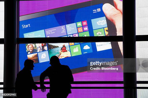 Two attendees are silhouetted against a Microsoft Corp. Poster at the Microsoft Developers Build Conference in San Francisco, California, U.S., on...