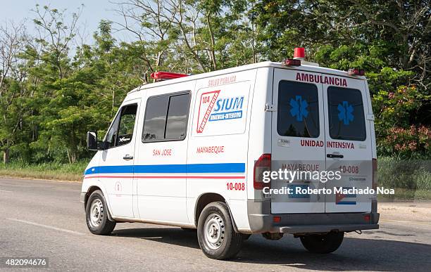 Everyday Cuban scenes: White ambulance part of the health care system drives down the Autopista Nacional. The ambulance has blue and red striped on...