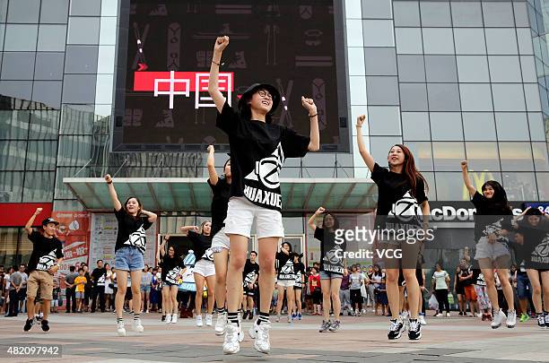 Fans of winter sports dance during a flash mob at a square with an electronic screen playing promotional film of 2022 Winter Olympic Games on July...