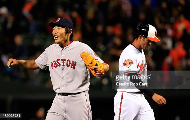 Koji Uehara of the Boston Red Sox celebrates in front of J.J. Hardy of the Baltimore Orioles following the Red Sox 6-2 win at Oriole Park at Camden...