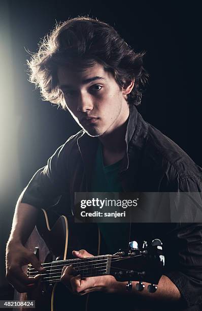 teenage boy playing acoustic guitar on stage - popular music concert stockfoto's en -beelden