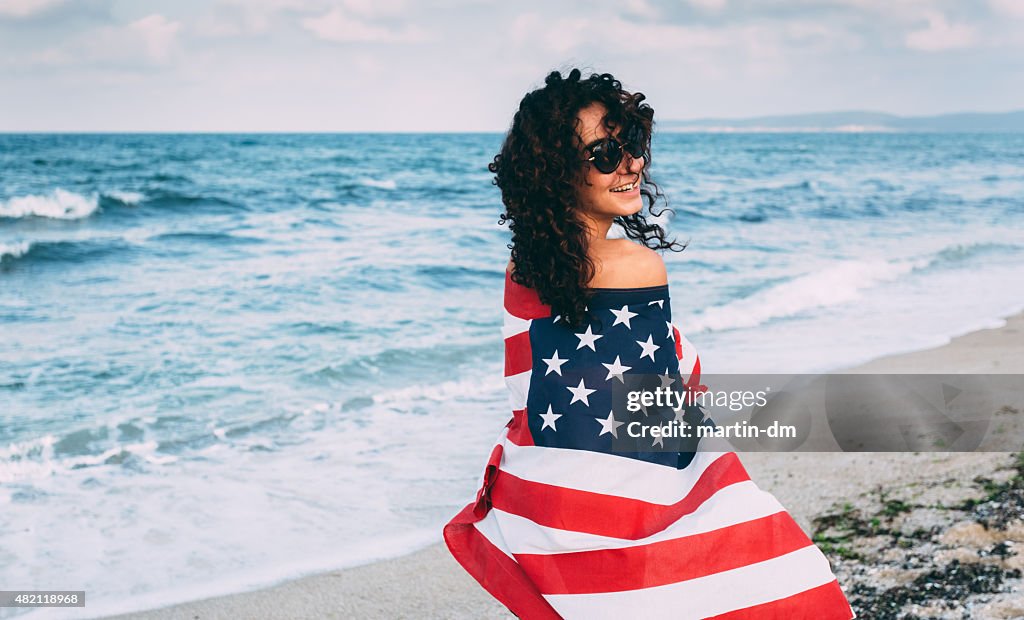Mädchen am Strand trägt die amerikanische Flagge