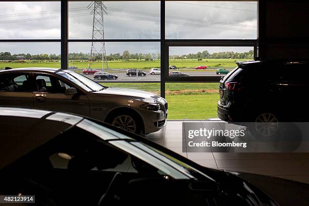 Automobiles sit inside a LeasePlan Corp. Used car leasing and contract hire showroom as traffic passes on a highway outside in Breukelen,...