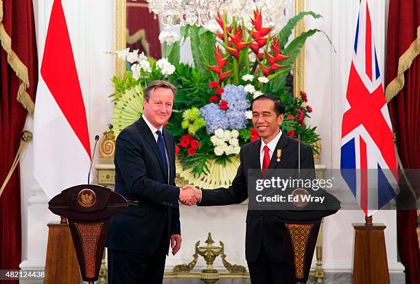 British Prime Minister David Cameron and Indonesian President Joko Widodo, shake hands after the signing of several memorandums of understanding...