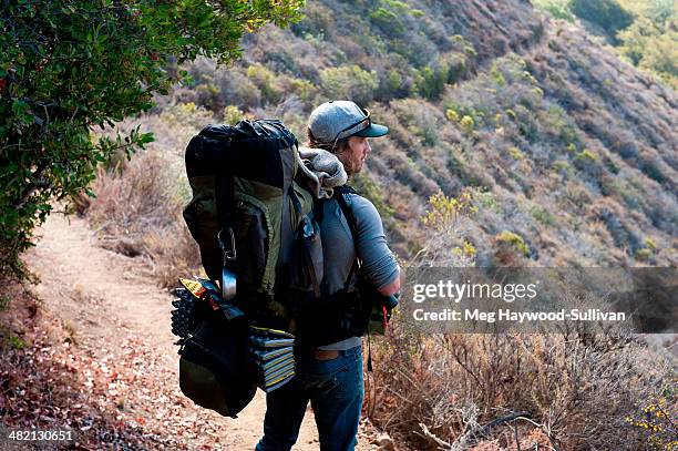 man hikes with heavy pack. - heavy rucksack stock pictures, royalty-free photos & images