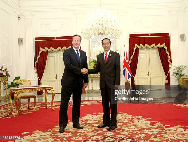 British Prime Minister David Cameron and Indonesian President Joko Widodo, shake hands at a joint briefing after the signing of several memorandums...