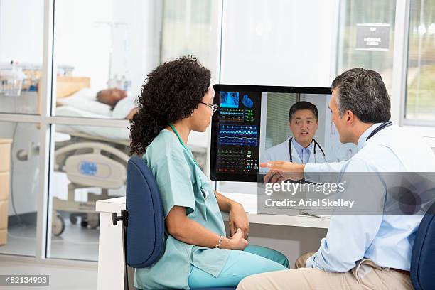 nurse having teleconference with doctors in hospital - medical partnership stock pictures, royalty-free photos & images