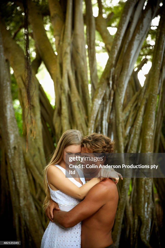 Caucasian couple hugging near banyan tree
