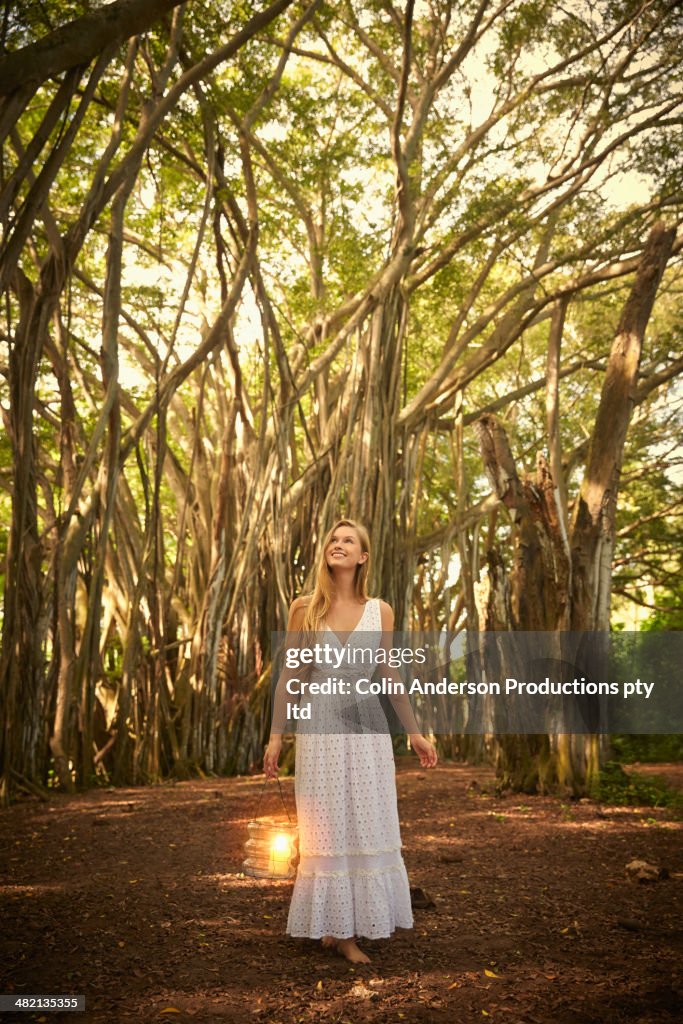 Caucasian woman walking below banyan trees in forest