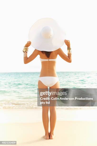 japanese woman in bikini and sun hat on beach - arm sun beach stock-fotos und bilder