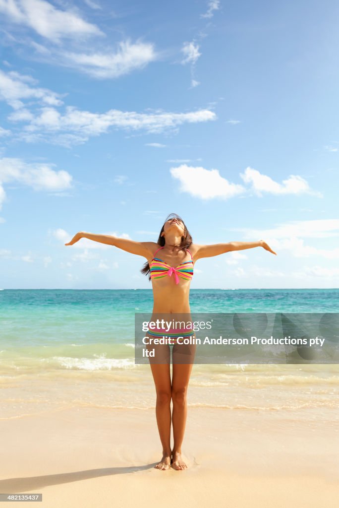 Japanese woman standing on beach with arms outstretched