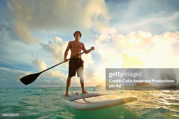 caucasian man on paddle board in water - paddle board men imagens e fotografias de stock