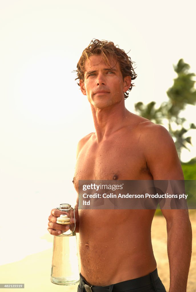 Caucasian man drinking water on beach