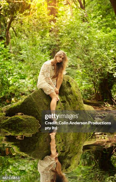 caucasian woman sitting at edge of creek in woods - donne bionde scalze foto e immagini stock