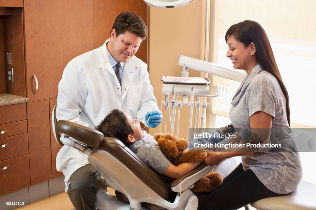 Dentist and mother watching boy in dentist's chair